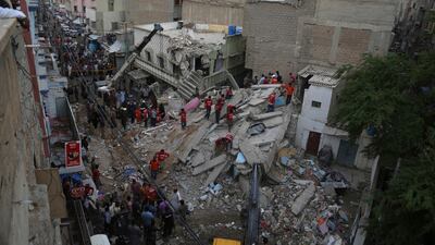 Volunteers look for trapped residents at the site of the building collapse. Shakil Adil / AP