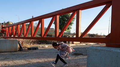 A Palestinian child passes under an Israeli barrier at the main entrance to Qusra village in the occupied West Bank. AFP