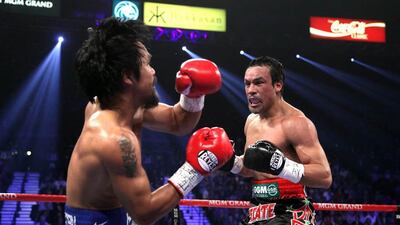 Manny Pacquiao, left, falls to to canvas after taking a punch from Juan Manuel Marquez in the 3rd round of their welterweight fight. John Gurzinski / AFP Photo