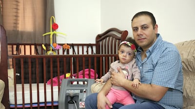 John Fam holds his daughter Marly who requires life saving injections to help her breathe during the winter. Victor Besa for The National