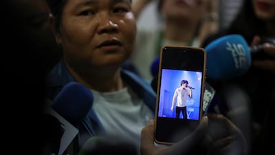 A woman shows a photo of her son, who is missing, while talking to the media at the police hospital morgue in the Thai capital. Reuters