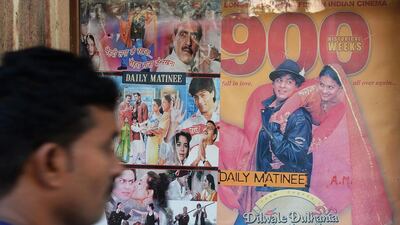 An Indian cinema-goer walks past a poster of a screening of the popular Bollywood Hindi movie 'Dilwale Dulhania Le Jayenge' which stars Shah Rukh Khan and is due to be taken off the big screen on Thursday, February 26, 2015. Indranil Mukherjee/AFP Photo