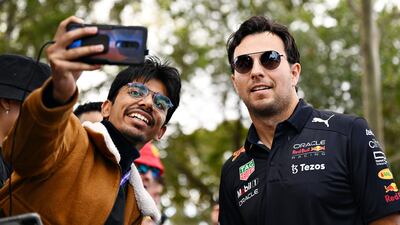 Red Bull driver Sergio Perez arrives at the circuit and poses for a photo with a fan. Getty