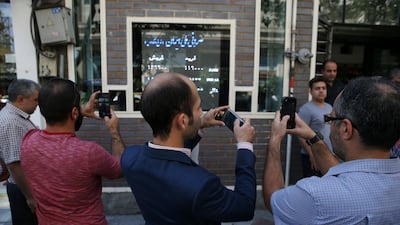 Iranians take pictures of an exchange shop screen showing various currency rates in downtown Tehran. Iranian currency has hit multiple record lows this year against the US dollar. AP