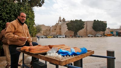 A Palestinian street vendor stands by his bread cart in the deserted Manger Square, opposite the Church of the Nativity in the West Bank. AFP