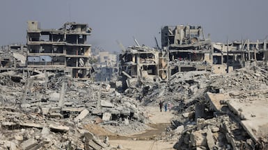 Palestinians walk past destroyed buildings following Israeli military operations in Gaza city. Reuters