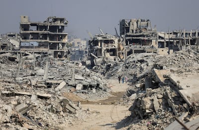 Palestinians walk past destroyed buildings in Gaza. Reuters