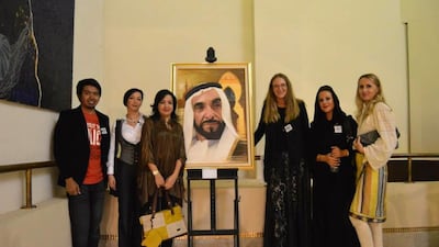 Members of the Abu Dhabi Art Collective (from L-R) JP Faderogao, Naida Akaeva, Loubna Adel, Katharina Moller, Cornelia Bacu, Mioara Corozel Cherki around the painting titled Father of a Nation by JP Faderogao. Image courtesy of JP Faderogao