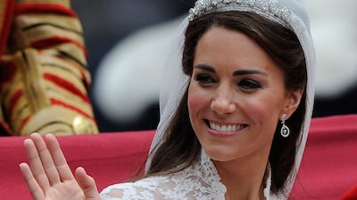 Catherine, Duchess of Cambridge waves as she travels beside husband Prince William, Duke of Cambridge in the 1902 State Landau carriage on the procession route along The Mall to Buckingham Palace after their wedding ceremony at Westminster Abbey on April 29, 2011 in London, England
