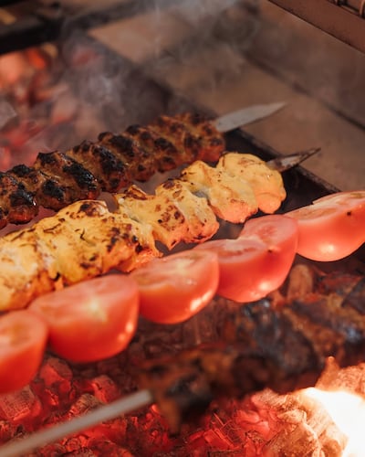 Saffron-marinated joojeh kebab and kabab koobideh are cooked over open coals then served with grilled tomatoes. Photo: Ariana’s Persian Kitchen