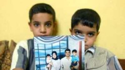 Hassan and Ali Mousa hold up a picture of their family, including their father Baha, during happier times.
