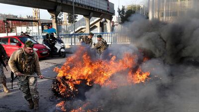 Lebanese soldiers try to remove burning tires set on fire by the anti-government protesters to block the southern entrance of a highway during a protest against the newly formed cabinet. AP