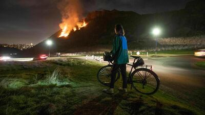 A woman looks at a gorse fire below Salisbury Crags in Holyrood Park, Edinburgh, Scotland. AP