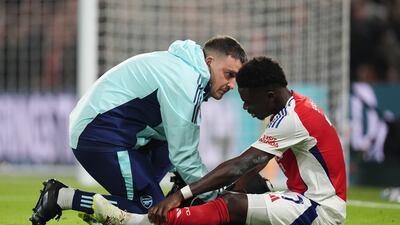 Arsenal's Bukayo Saka receives treatment from medical staff after going down injured against Chelsea. PA