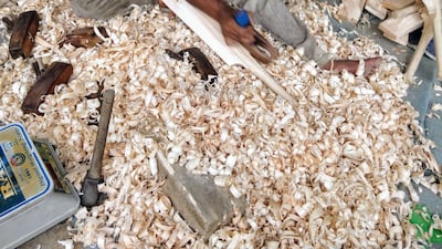 A worker engaged in shearing the correct amount of wood and shaping the bat.