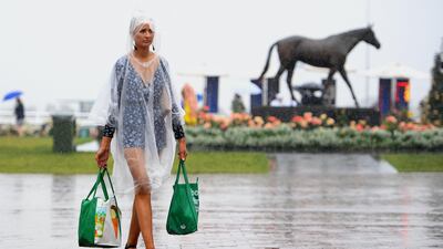 A woman wearing a raincoat and carrying shopping bags arrives for the annual Melbourne Cup, the world's richest two-mile handicap, at Flemington Racecourse in Melbourne, Australia. AFP