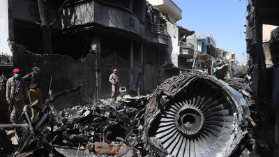 Security personnel stand beside the wreckage of a plane at the site after a Pakistan International Airlines aircraft crashed in a residential area in Karachi. AFP