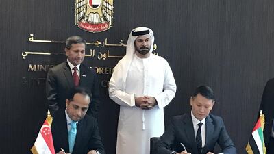 Sopnendu Mohanty, the chief fintech Officer of Monetary Authority of Singapore, left, and Richard Teng, the chief executive of FSRA of ADGM sign the agreement in the presence of Mohammed Al Gergawi, centre, Minister of Cabinet Affairs. Courtesy Abu Dhabi Global Market