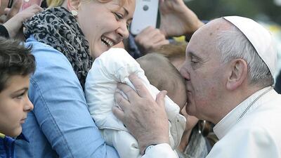Pope Francis kisses a baby on February 16, 2014, as he is welcomed by faithfuls upon his arrival for a visit to the parish of San Tommaso on the outskirts of Rome. Andreas Solaro / AFP photo