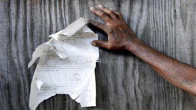 A Thai carpenter reads one of the court issued eviction notices to the informal settlers of wood workers, at their railway line home and workplace, on the edge of Bangkok's Klong Toey port. The community here is trespassing, according to the Bangkok Port Authority, who want the land back for road expansion. Barbara Walton / EPA