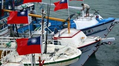 A fisherman raises a Taiwanese national flag as several dozen fishing boats set out from the Suao harbor, northeastern Taiwan, to the disputed islands in the East China Sea.