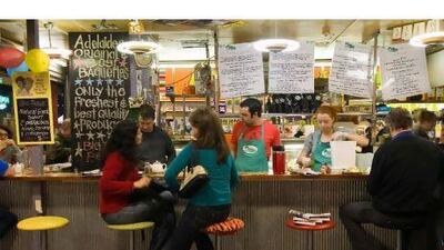 Locals sit down for their morning coffee at the Big Table cafe in Central Market. Alamy