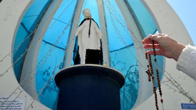A Christian woman carries a rosary as she prays in front of Virgin Mary's statue in a Christian neighborhood of Ain Remmaneh on the eve of Good Friday in Beirut. EPA