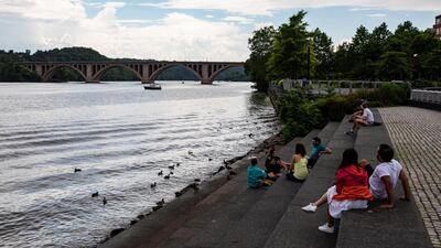 People sit along the Georgetown Waterfront on the Potomac River despite off and on rain in Washington, DC, US, 20 June. Samuel Corum / EPA