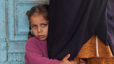 A Syrian girl holds on to her mother.