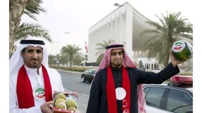 Two men from the Kuwaiti youth movement Kafi (Enough) hold watermelons as part of a protest calling for the resignation of Kuwait's prime minister.