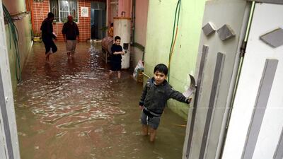An Iraqi man stands with his sons at his flooded house in Mosul, northern Iraq, on December 1, 2018. EPA