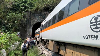 People walk next to a train which derailed in a tunnel north of Hualien, Taiwan, in this handout image provided by Taiwan's National Fire Agency. Reuters