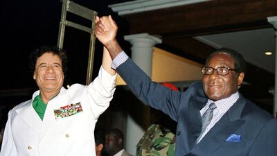 Libyan leader Col Muammar Qaddafi and Mugabe greet supporters outside State House in Harare, Zimbabwe July 12, 2001. Reuters