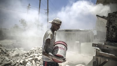Workers with the rubble of buildings destroyed during the May rocket attacks. Sanad Latefa for The National