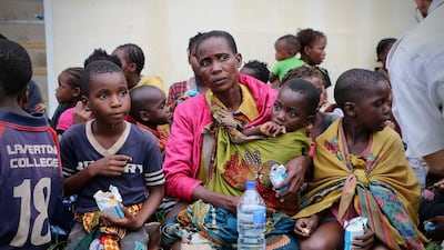 Displaced people receive food and drink after arriving at the airport of Beira in central Mozambique. AFP