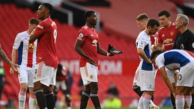Manchester United midfielder Paul Pogba holds his boot as he talks to referee Martin Atkinson after he went down in the box. AFP