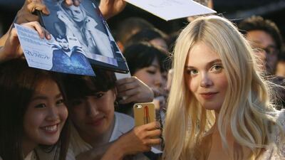 Actress Elle Fanning poses for pictures with fans as she makes an appearance before fans at the Japan premiere of Maleficent in Tokyo June 23, 2014. The movie will be screened to the public in Japan on July 5. Reuters