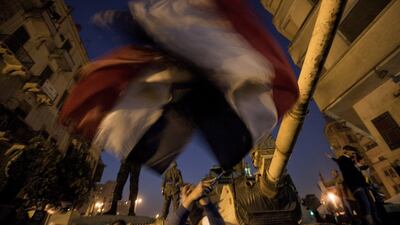 Anti-government protesters wave Egyptian flags in front of an army tank as demonstrators at Cairo;s Tahrir Square react after President Hosni Mubarak stepped down.