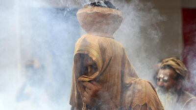 A Sadhu or a Hindu holy man covers his face as an earthen pot with burning "Upale" (dried cow dung cakes) rests on his head during a prayer ceremony at the Simhastha Kumbh Mela in Ujjain. Jitendra Prakash / Reuters