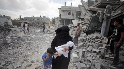 A Palestinian woman passes by rescuers inspecting the rubble of destroyed houses after Israeli strikes in Rafah refugee camp, southern Gaza Strip. AP