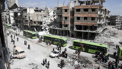 Syrian civilians and rebel fighters prepare to board buses during the evacuation from Arbin in Eastern Ghouta on the outskirts of Damascus. Abdulmonam Eassa / AFP