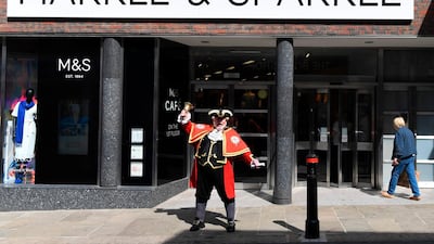 A town cryer rings his bell outside a branch of Marks and Spencer. The retailer has rebranded as Markle and Sparkle for the weekend in honour of the Royal Wedding. Paul Ellis / AFP