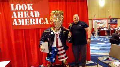 A conference attendee poses next to a statue of Donald Trump. Artist Tommy Zegan says the statue's US flag-themed shorts symbolise that the former president is a patriot. Reuters