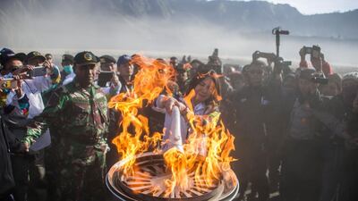 Former Indonesian badminton player Susi Susanti lights the torch for the Asian Games during the torch relay at the site of the Mount Bromo volcano in Probolinggo, East Java province. Juni Kriswanto/AFP