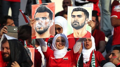 A supporter holds images of Syria's Omar Al-Soma and Omar Khrbin. AFP