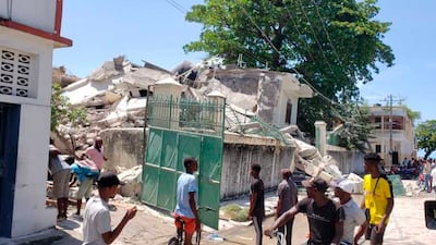 People stand outside the residence of the Catholic bishop after it was damaged by the earthquake.