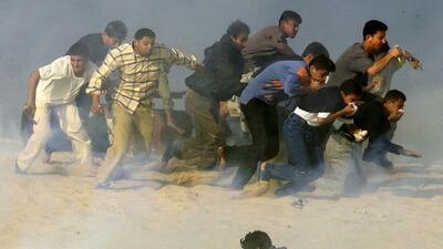 Palestinians try to run away from Israeli soldiers firing tear gas during Palestinian-Israeli clashes in the southern Gaza Strip town of Khan Younis in this October 20, 2000. Reinhard Krause / Reuters