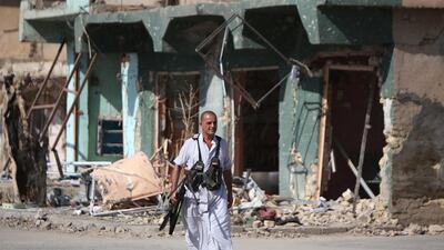 ISIL may not be able to maintain its momentum. Above, an Iraqi fighter walks past a building in Dhuluiya after government security forces and militia retook the city from ISIL extremists. Ahmed Al Rubaye / AFP