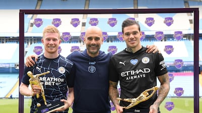 Ederson of Manchester City holds the Golden Glove Award and Kevin De Bruyne holds the Playmaker Award alongside Pep Guardiola. Getty