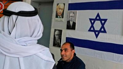 An Arab-Israeli man arrives at a poling station, decorated with portraits of Israeli politicians, to cast his ballot for the parliamentary election in the Bedouin town of Rahat near the southern Israeli city of Beersheba on March 2, 2020. AFP